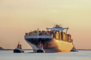 Tug boats guiding a cargo ship to port.