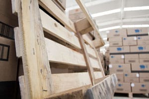 Empty pallet leaning against a stack of pallets in warehouse
