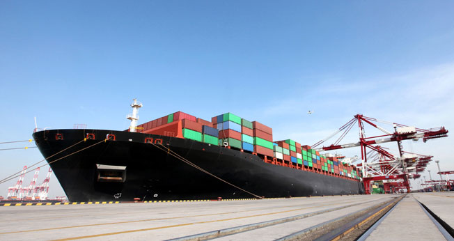 Container ship docked at a port and loaded with shipping containers.